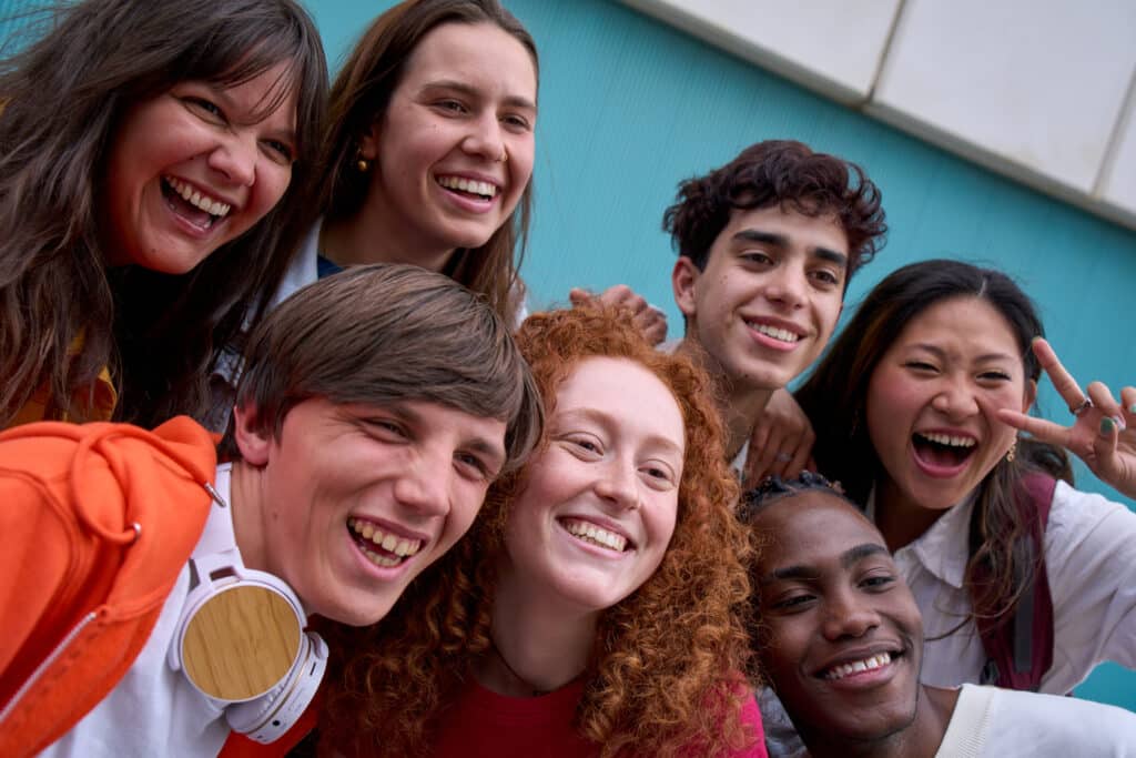 Selfie of smiling multi-ethnic group of college students together outdoors. Joyful young friends.
